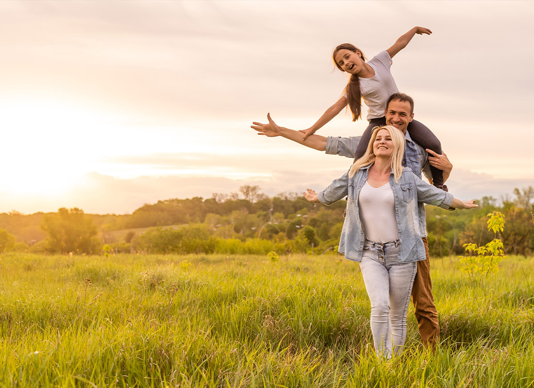 Personal Insurance - Young Family Having Fun Together in a Field During Sunset