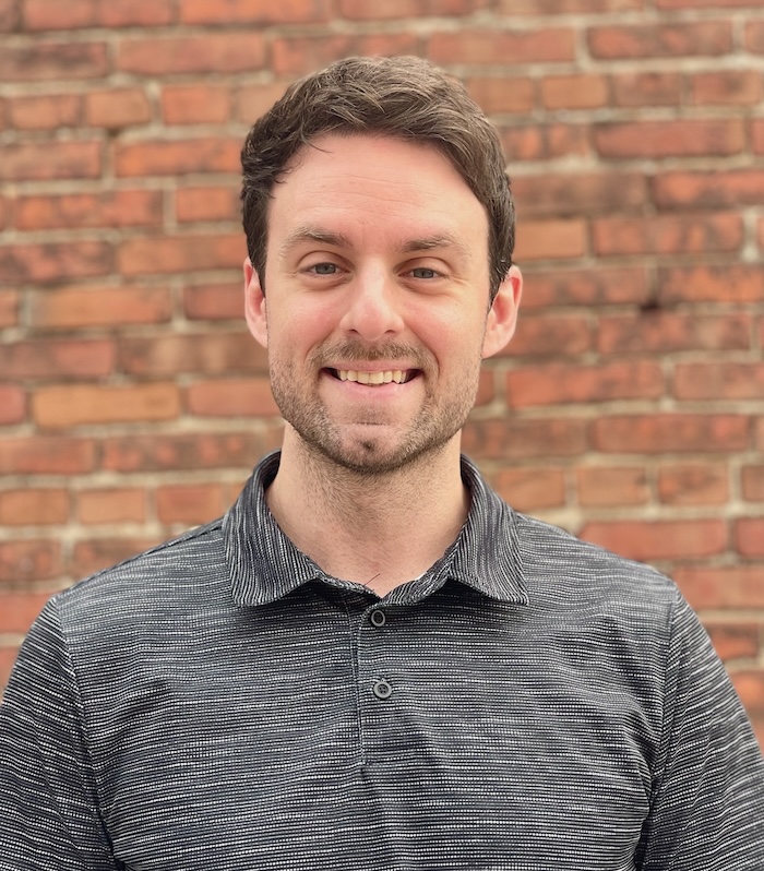 Meet Our Team - Professional and Welcoming Group at a Conference Table Faces the Camera, Team Leader Sitting on the Table with Arms Folded